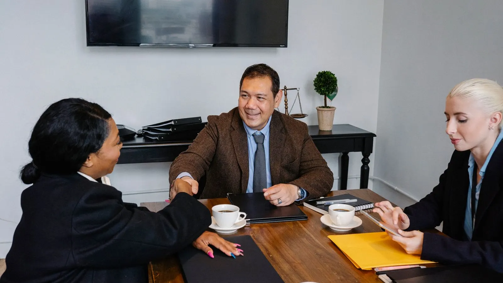 Profissionais fechando um acordo em volta de uma mesa de reunião