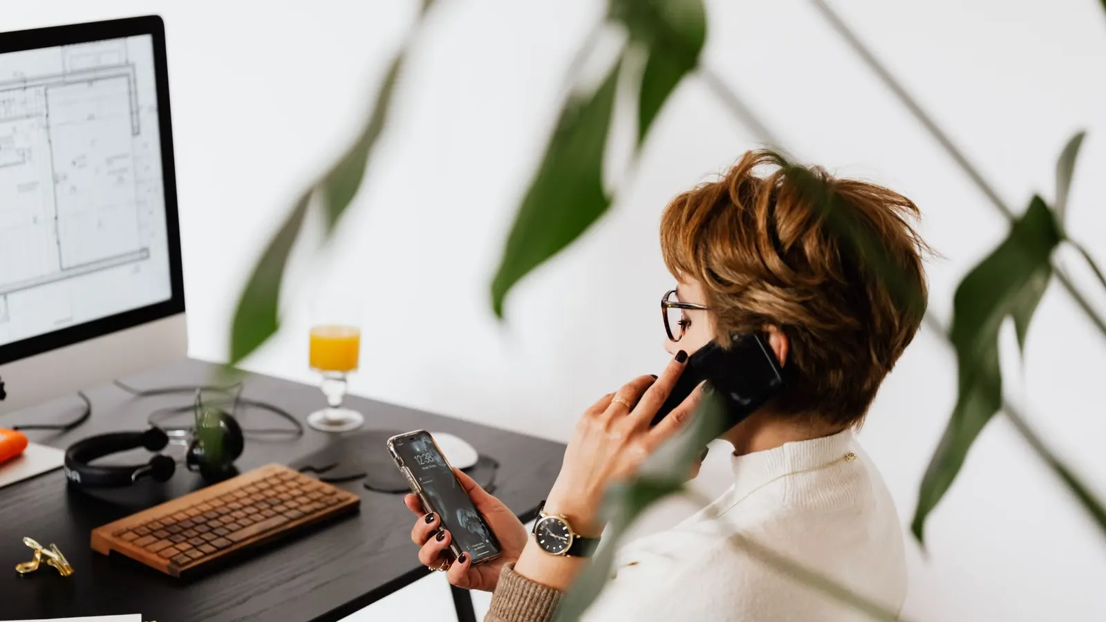 Profissional fala ao celular sentada à mesa do escritório