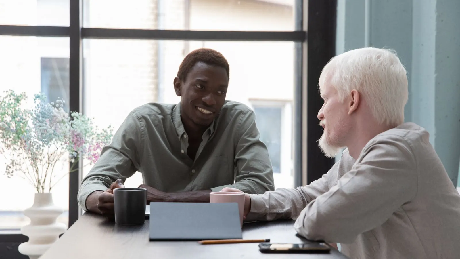 Dois sócios de terno conversam à mesa do escritório